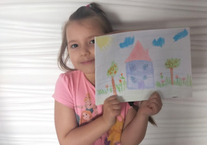 Dziewczynka pokazuje rysunek domu